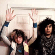 two people raising their hands in the air in front of a wall