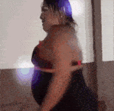 a woman with purple hair and a black dress is dancing
