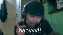 a man wearing headphones says " babyyy " in a room