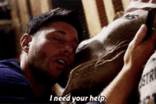 a man is laying on a bed holding a bag and says i need your help