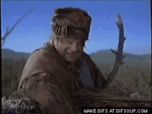 a man in a native american outfit is holding a stick in his hand .