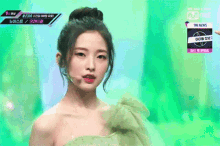 a woman in a green dress is standing in front of a mnet sign