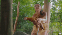 a woman is sitting on a tree branch holding a stuffed animal .