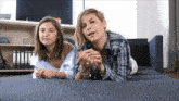 a woman and a girl are laying on a couch looking at something