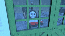a blue train is looking out of a green window in the rain