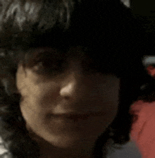 a close up of a woman 's face with curly hair and a red background .