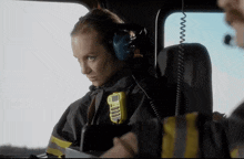 a woman in a firefighter uniform has a yellow walkie talkie on her shoulder