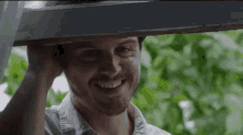 a man is holding a piece of wood over his head and smiling .