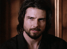 a man with long hair and a beard is smiling for the camera