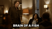 a man in a suit is standing next to a woman in a suit and the words brain of a fish are above them