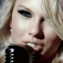 a close up of a woman singing into a microphone with her eyes closed