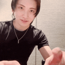 a man wearing a black t-shirt and a necklace with a cross on it