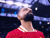 a man with a beard is wearing a red and yellow striped shirt and looking up