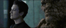a man and a monster are standing next to each other and looking at each other .