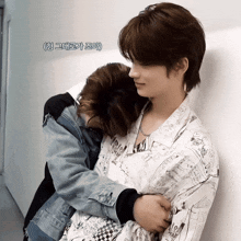 a man in a denim jacket is hugging another man in a shirt that says ' snoopy ' on it