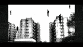 a black and white photo of a group of people hanging from a building