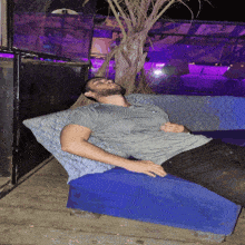 a man in a grey shirt is laying on a blue chair