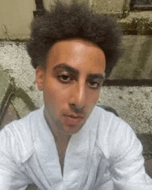 a man in a white robe is taking a selfie with his phone .