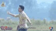 a man in a colorful shirt is standing in a field with his arms wide open