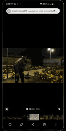 a phone screen shows a video of a man standing in a park at night