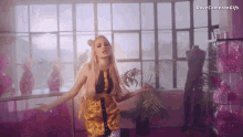 a woman in a yellow and black dress is dancing in a room with dove cameron gifs written on the bottom