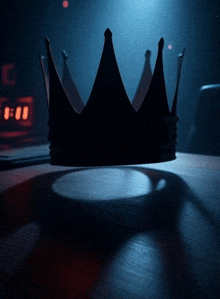 a crown sits on a wooden table in front of a clock that reads 6:00