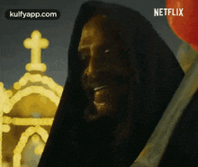 a man in a hooded robe is holding a red balloon .