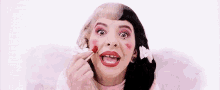 a woman with a tooth missing is applying red lipstick to her lips .