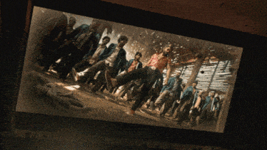 a large screen shows a group of people walking in a dark room