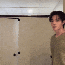 a man in a green shirt is standing in front of a closet