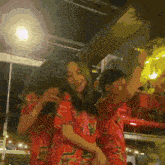 a couple of women in red floral shirts are dancing together