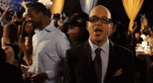 a man in a suit and tie stands in a crowd of people