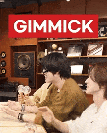 a group of people are sitting at a table with a sign that says gimmick
