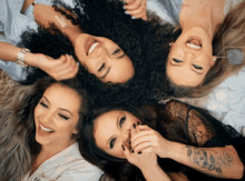 four women are laying in a circle and smiling