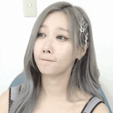 a woman with gray hair and a star in her hair makes a funny face