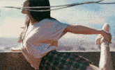 a woman in a plaid skirt is stretching her legs on a balcony .