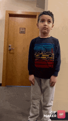 a young boy is standing in front of a door that has the number 302 on it