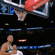 a basketball is going through a hoop with a konica minolta logo on it