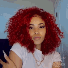 a woman with red curly hair is wearing a white t-shirt and a gold necklace .