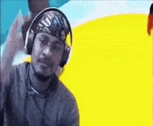 a man wearing headphones and a bandana is looking at the camera .