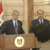 a man stands behind a podium that has a emblem on it