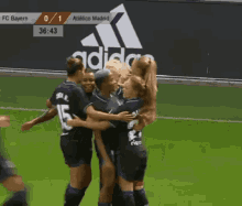 a group of women hugging each other on a soccer field