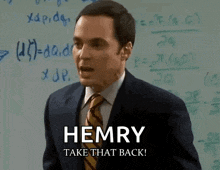 a man in a suit and tie is standing in front of a white board and says " hemry take that back "