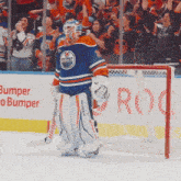 a hockey goalie stands in front of a bumper o bumper banner