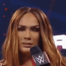 a woman with long brown hair is holding a microphone in her hand .