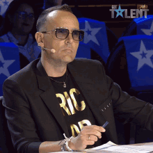 a man wearing sunglasses and a black shirt that says ric