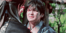 a man with blood on his face is looking at another man with blood on his face
