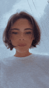 a woman with short hair is wearing a white shirt and looking at the camera