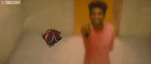 a man in a pink shirt is pointing at a fly