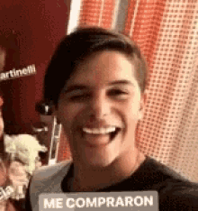 a young man is smiling with a sign that says `` me compraron '' .